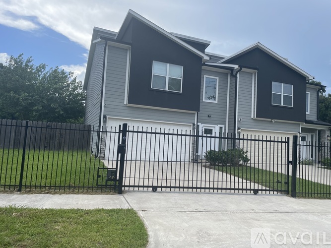 A two-story house with a black fence in front.