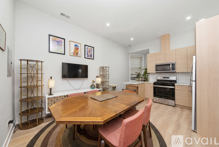 A modern kitchen with a wooden table and chairs, a TV, and a refrigerator.