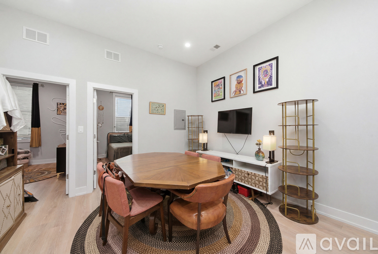 A dining room with a wooden table surrounded by chairs and a TV mounted on the wall.