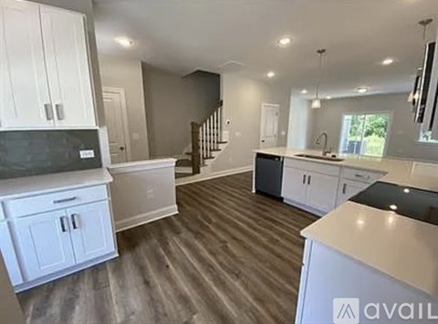 A spacious kitchen with white cabinets and a wooden floor.
