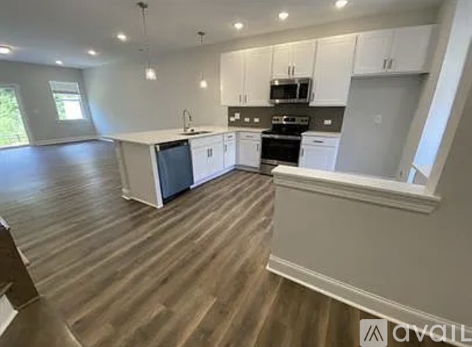 A kitchen with white cabinets and a wooden floor.