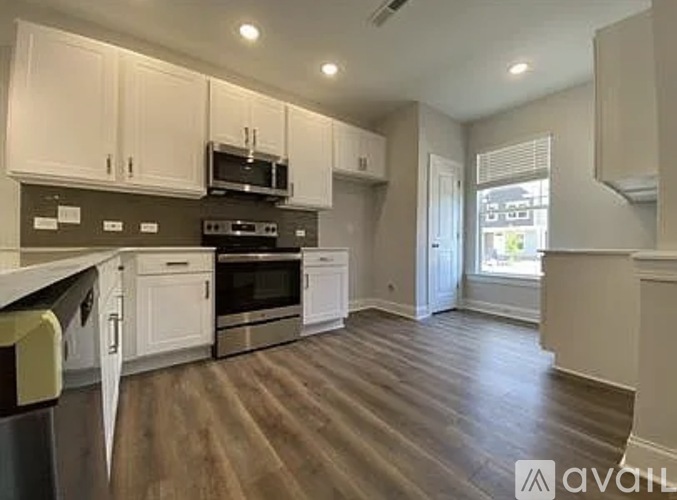 A kitchen with white cabinets and a wooden floor.