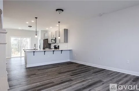 A spacious kitchen with white cabinets and a wooden floor.