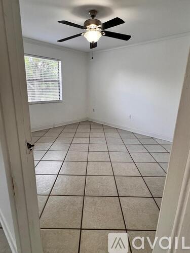 A room with a ceiling fan and tile flooring.