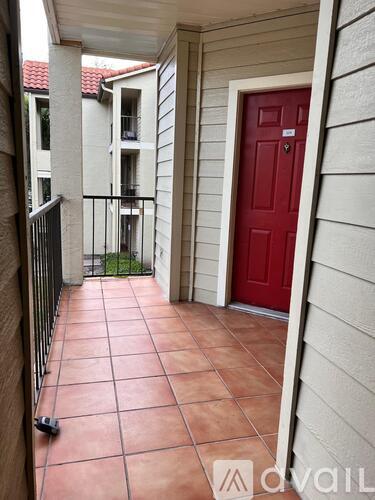 A red door is on the right side of a balcony.