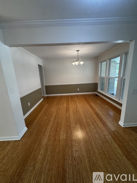 A room with wooden flooring and a chandelier hanging from the ceiling.