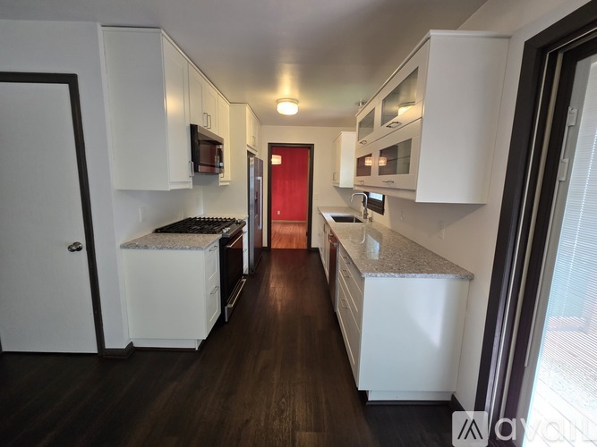 A kitchen with white cabinets and a red door.