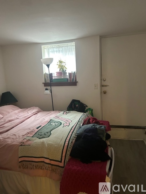 A bedroom with a bed covered in a comforter and a cat sitting on the bed.