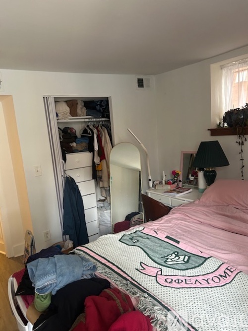 A bedroom with a pink bedspread and a white bed.
