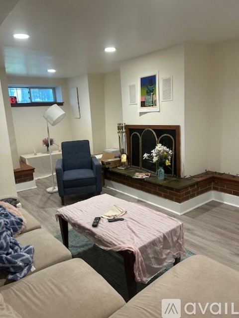 A living room with a blue chair and a pink tablecloth.
