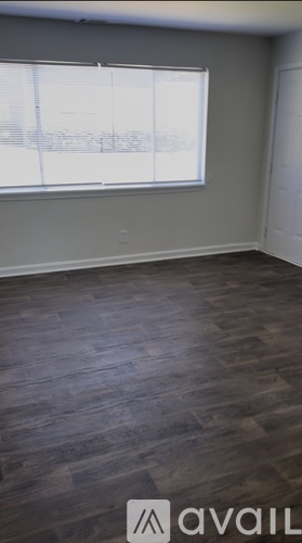 A room with a window and wooden flooring.