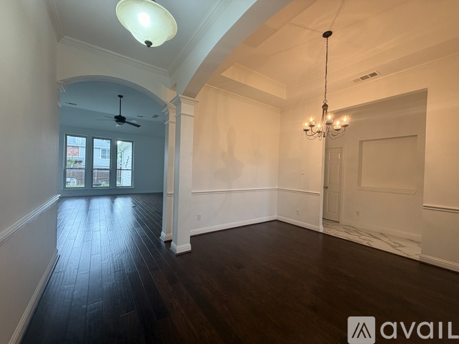 A room with a chandelier, a ceiling fan, and a door.