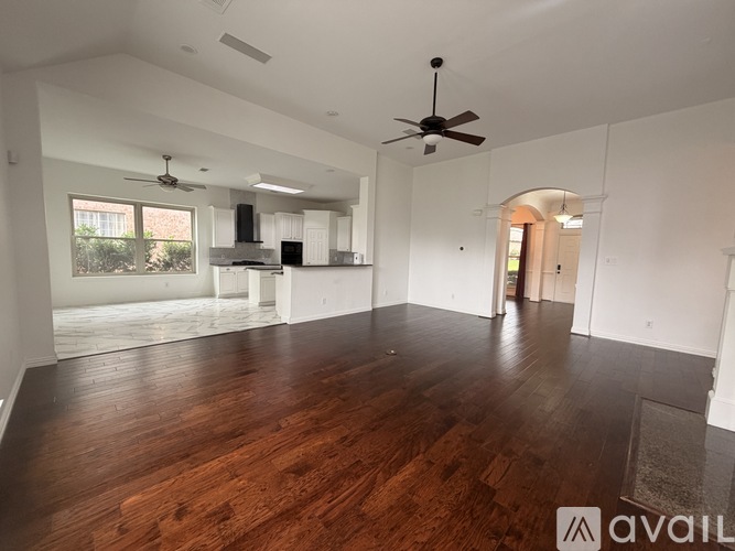 A spacious room with wooden floors and a ceiling fan.
