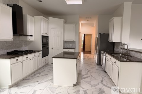 A kitchen with white cabinets and black appliances.