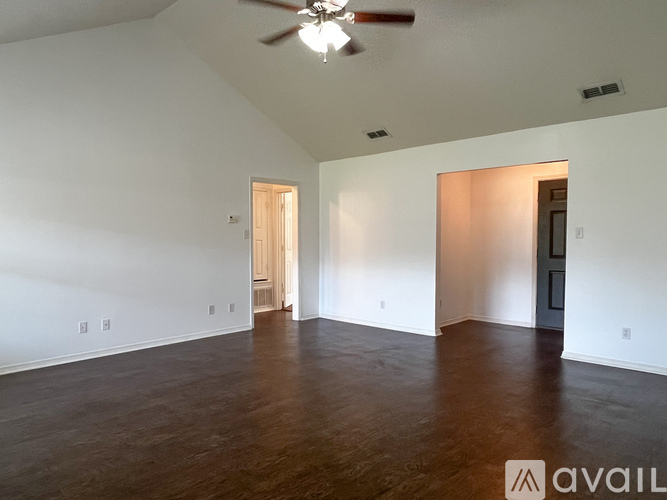 A spacious room with wooden floors and a ceiling fan.