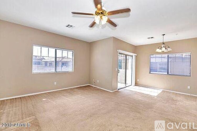 A spacious room with a ceiling fan and two windows.