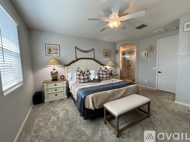 A bedroom with a bed, bench, and a ceiling fan.