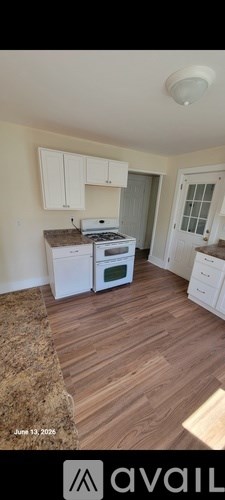 A kitchen with white cabinets and a wood floor.