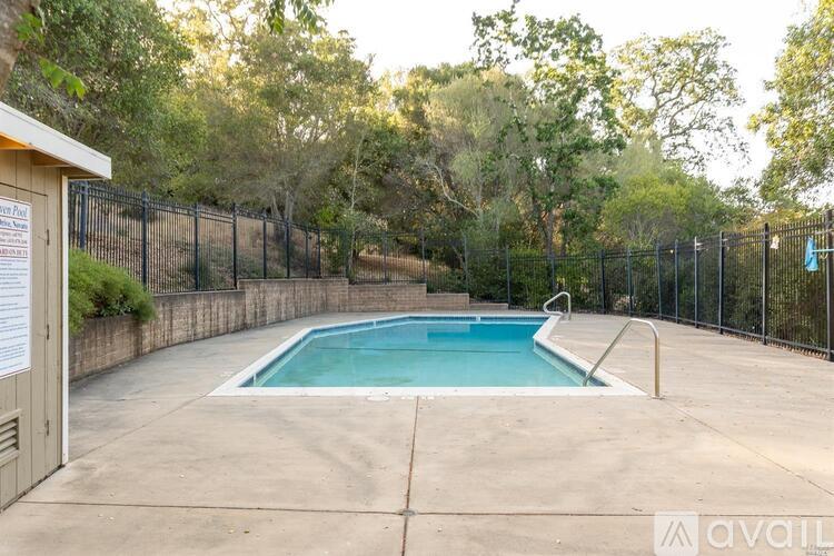 A pool surrounded by a black fence with a sign on the left.