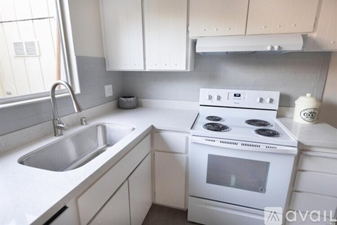 A white kitchen with a stove and sink.
