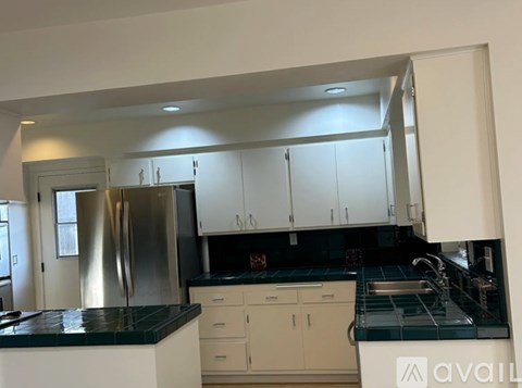 A kitchen with white cabinets and a black countertop.