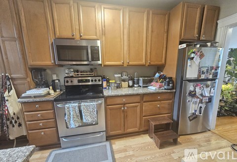 A kitchen with wooden cabinets and a stainless steel refrigerator.