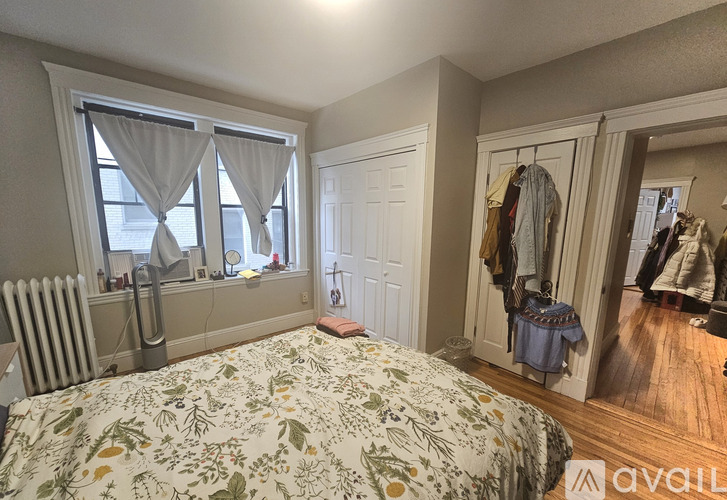 A bedroom with a large bed and a closet with clothes hanging.