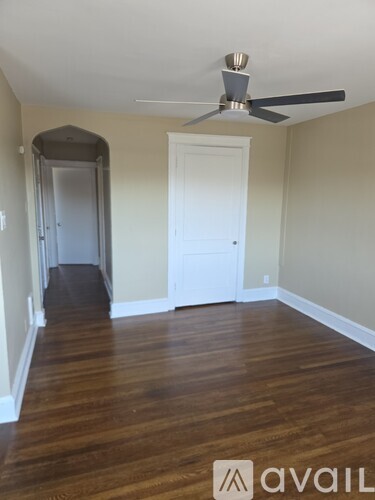 A room with a fan and a doorway leading to another room.