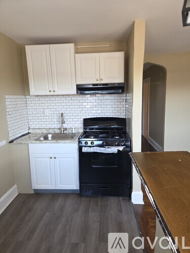 A kitchen with a black stove top oven and white cabinets.