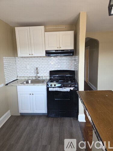 A kitchen with a black stove top oven and white cabinets.
