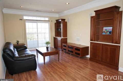 A living room with a black leather couch, wooden coffee table, and a wooden cabinet with a painting on it.
