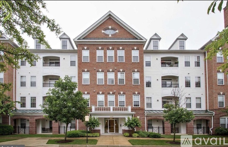 A large brick building with a white trim and a balcony on the second floor.