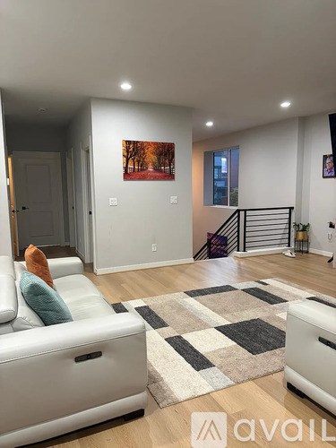 A living room with a white couch and a painting on the wall.