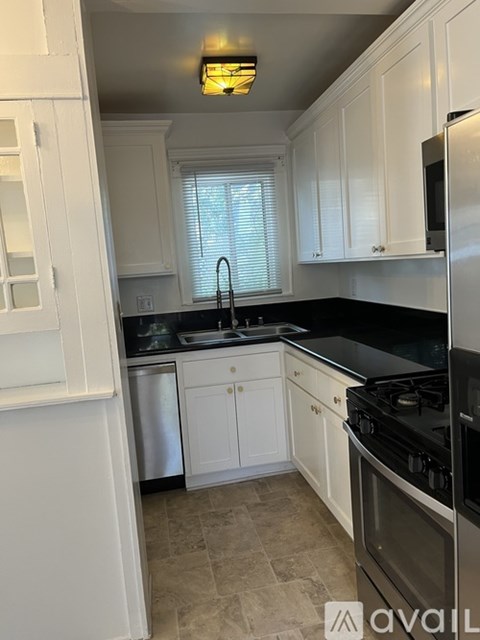 A kitchen with white cabinets and a black countertop.
