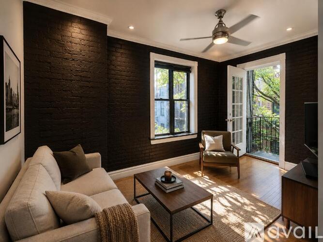 A living room with a couch, a chair, a coffee table, and a ceiling fan.
