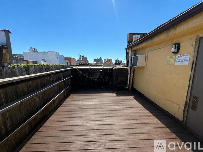 A wooden deck with a yellow building and a sign on it.