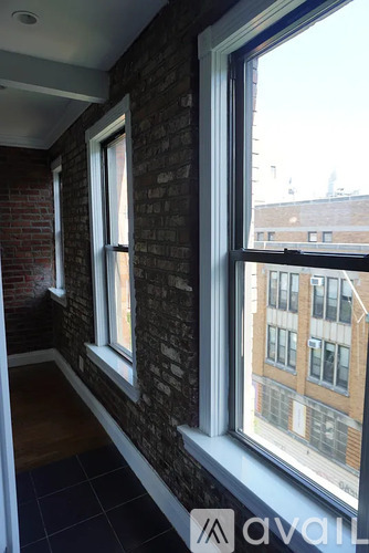 A room with a brick wall and a window overlooking a city.