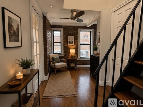 A living room with a staircase on the right and a chair with a cushion on the left.