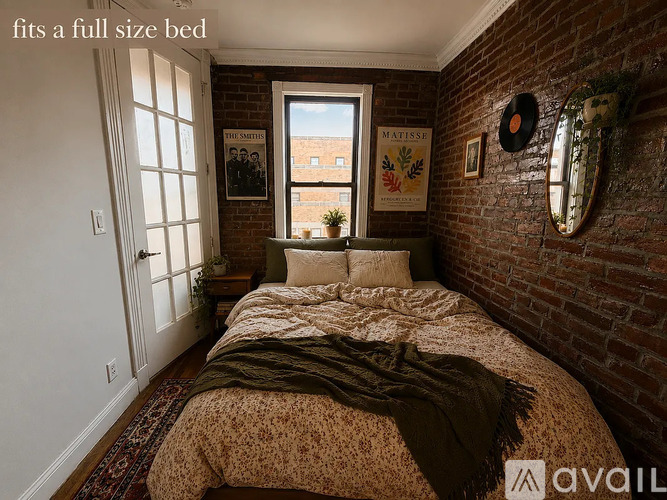 A bedroom with a full-size bed and a brick wall.