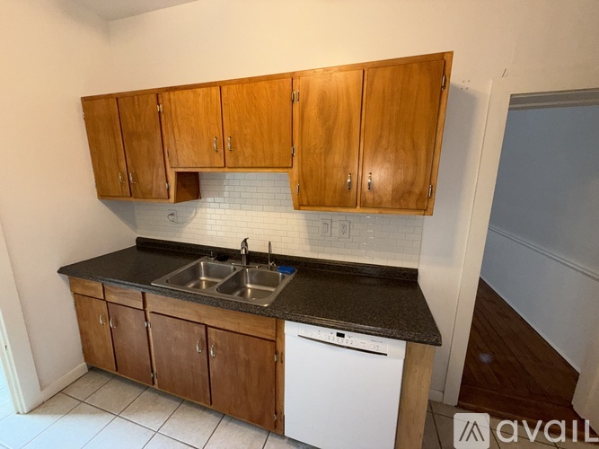 A kitchen with wooden cabinets and a white dishwasher.
