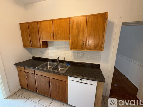 A kitchen with wooden cabinets and a white dishwasher.