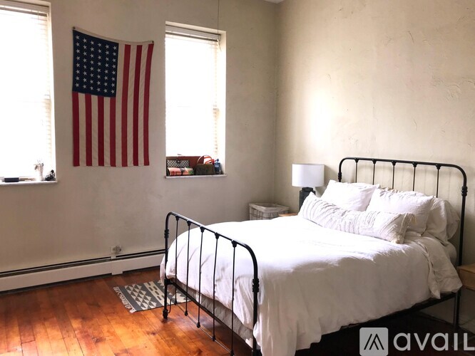 A bedroom with a bed, lamp, and American flag.