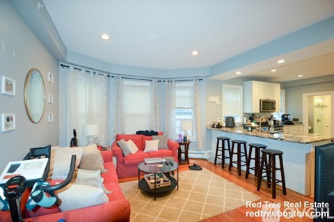 A living room with a red couch and a bar area.