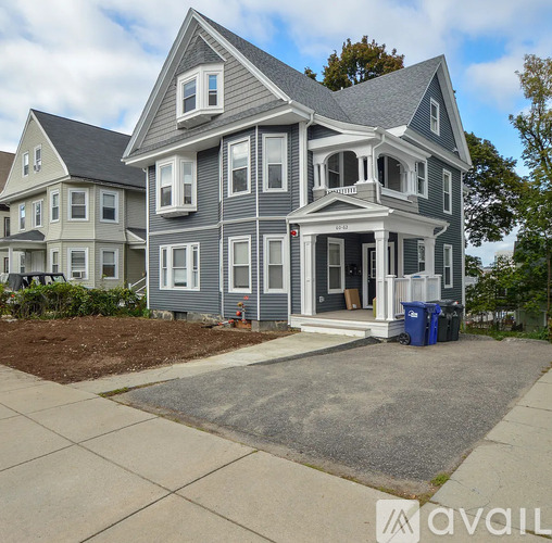A two-story house with a grey exterior and a front porch.