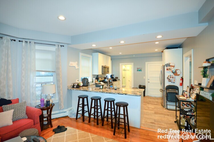 A kitchen with a bar area and a red couch.