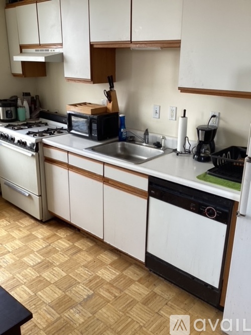 A kitchen with white cabinets and a wooden floor.