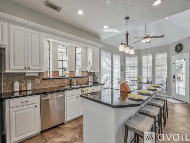 A kitchen with white cabinets and a black countertop.