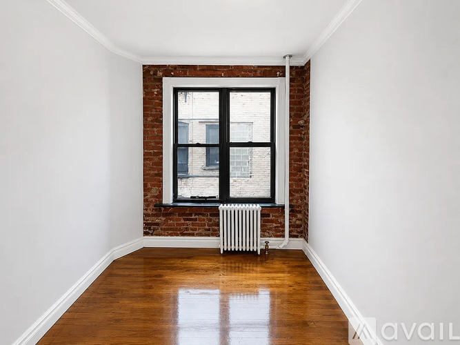 A room with a brick wall and a window with a white frame.