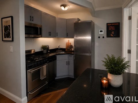 A modern kitchen with a black countertop and stainless steel appliances.