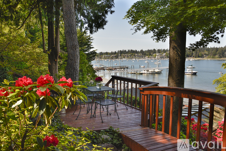 A deck with a table and chairs overlooks a body of water with boats.